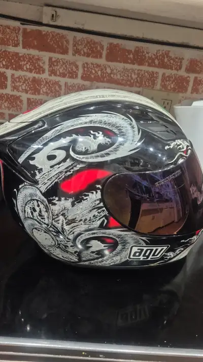 This is an AGV motorcycle helmet featuring a unique dragon design, offering both style and protectio...