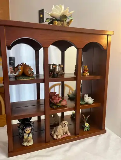 The shelf has a traditional design with three columns of open shelving, each section topped with a d...