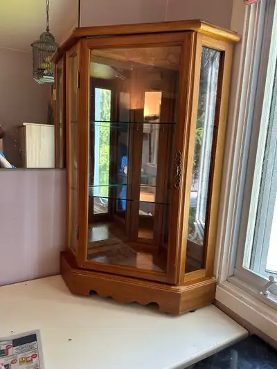 Voici une vitrine d'angle en bois avec des étagères en verre, idéale pour exposer vos objets de coll...