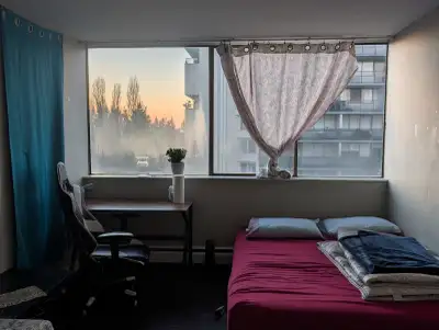 The bigger bedroom in a 2-bedroom apartment near Lougheed SkyTrain station. The room has a bed, desk...