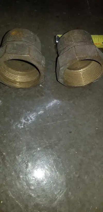 These are two new, brass plumbing fittings, likely for connecting pipes or fixtures in a plumbing sy...