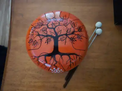 This pre-owned steel tongue drum, featuring a beautiful tree design in a vibrant orange finish, is r...