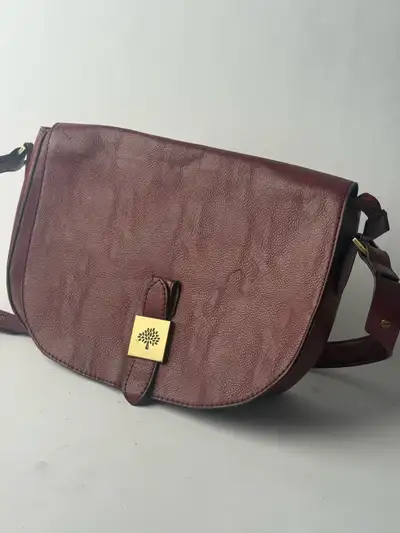 This pre-owned Mulberry handbag features a rich, deep burgundy pebbled leather exterior, complemente...