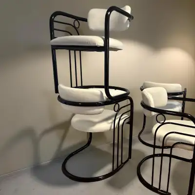 Rare set of postmodern black metal sculpted chairs. Each chair has a white vinyl seat and black chro...