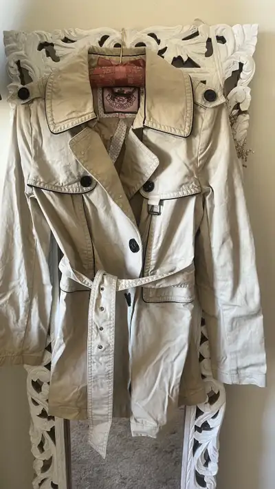 Juicy Couture trench coat in size small with a stylish beige colour and contrasting black trim, perf...