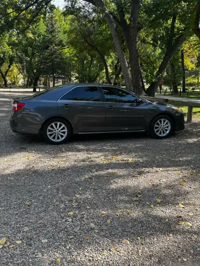 This reliable Toyota Camry Hybrid is a fuel-efficient sedan, featuring a sleek grey exterior and a c...