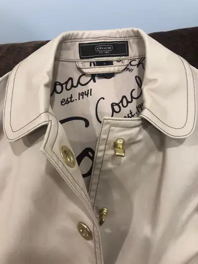 This is a beige Coach trench coat, size 4, perfect for spring or fall. It is in excellent condition,...