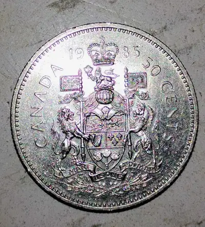 This is a 1985 Canadian 50-cent coin featuring the Canadian coat of arms, a piece of history in your...