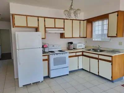 A partially furnished room with a shared open kitchen, dining area and washroom in a 2-bedroom suite...
