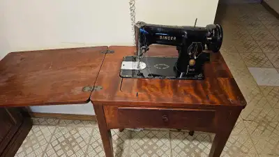 This vintage Singer sewing machine, complete with its original table, is a fantastic find for collec...