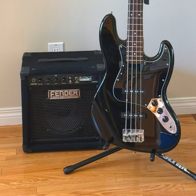 Black-on-black Squier Affinity Jazz Bass with knurled black metal control knobs and Fender Rumble 15...