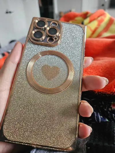This is a cute iPhone case with a glittery silver and gold design, and a heart-shaped MagSafe ring....