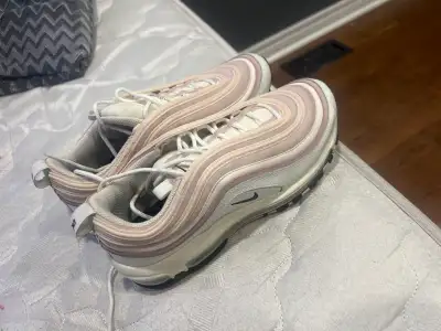 These are a pair of Nike Air Max 97 running shoes, featuring a stylish pink and white colourway and...