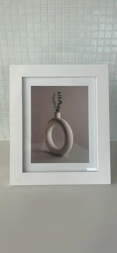 This is a white picture frame with a print of a vase. It's in great condition and ready to add some...
