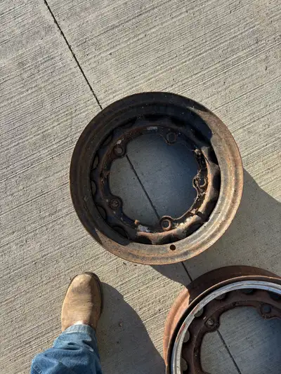 These antique wheel rims, featuring a classic wire-spoke design and heavy-duty steel construction, a...
