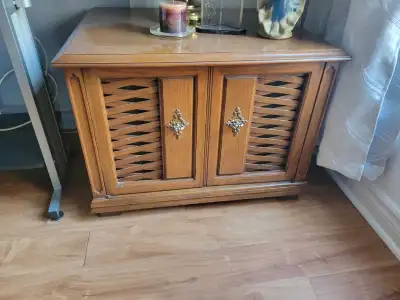 Ce table de rangement, malgré son âge, offre toujours un espace de rangement pratique et un charme r...