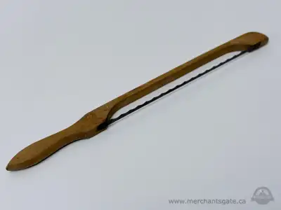 Vintage wooden handled cutting tool with a serrated metal blade secured to the handle. Likely used a...