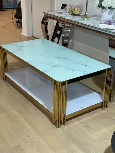 This used coffee table features a white marble-patterned glass top and a brilliant gold frame, compl...