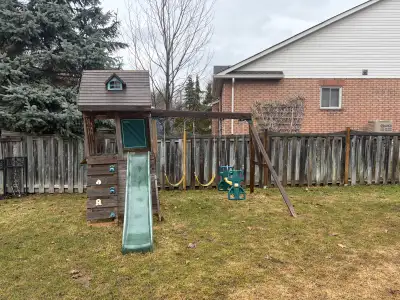 This used kids playset features a slide, monkey bars, a small clubhouse-style structure, and a swing...