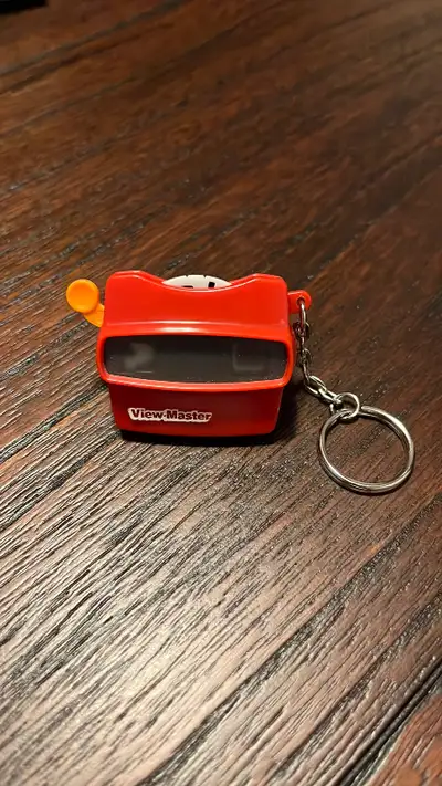 Mini ViewMaster toy on a keychain. Removable reel has cartoon images like a bird and clown. Works. I...