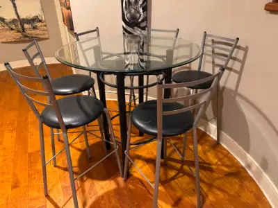 42 inch diameter, 42 inch tall glass table with six bar stool style chairs in good condition. Glass...