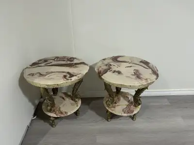 These are used end tables, each featuring a faux marble top and ornate gold-tone legs with a second...