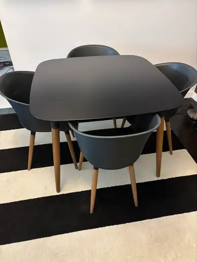 Black table with wooden legs with four plastic chairs with wooden legs. Like new. Great for the back...