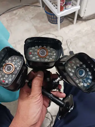 Three wireless security cameras, each with an antenna and mounting stand. Includes power adapters. I...