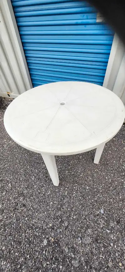 This is a used round plastic outdoor table, perfect for your patio or garden. It's sturdy and ready...