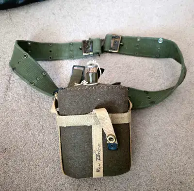 Canteen: Classic military-style metal or heavy plastic canteen with an olive drab finish. Cover: Aut...