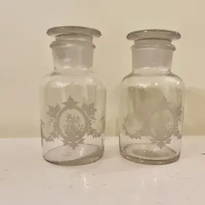 Pair of French Country Cottage apothecary bottles, adorned with delicate floral leaf etchings. These...