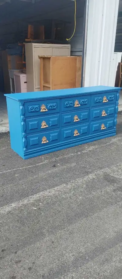 This is a used nine-drawer dresser, painted in a vibrant blue with gold hardware, perfect for adding...