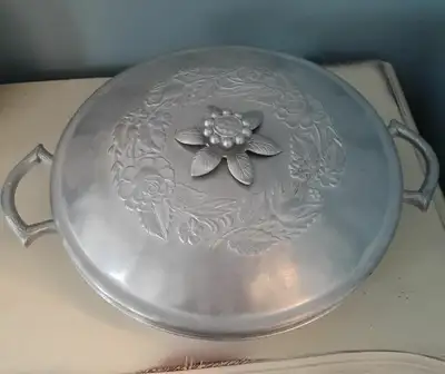Top has an embossed floral wreath and daffodil lid while the bottom features bamboo looking handles...