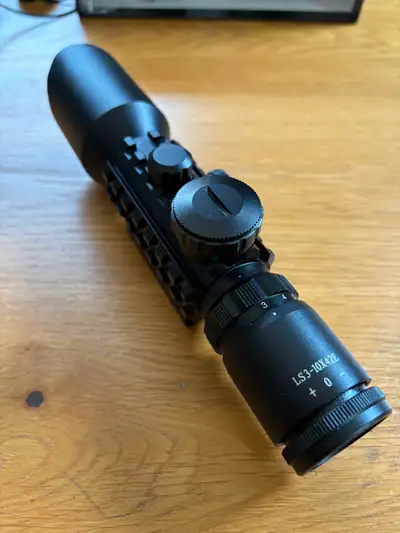 Small black anodized aluminum rifle scope with crosshairs and also red or green illuminated cross ha...