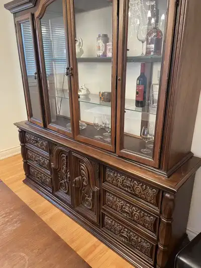 Beautiful vintage solid wood china cabinet with intricate carved details and glass display doors. Th...