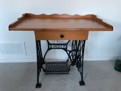 This is a beautiful piece. Solid wood pine table top with drawer secured to cast iron vintage singer...