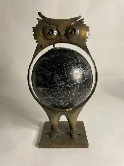 Vintage globe held by a brutalist‑style metal owl. It’s a striking mix of sculpture and function — t...