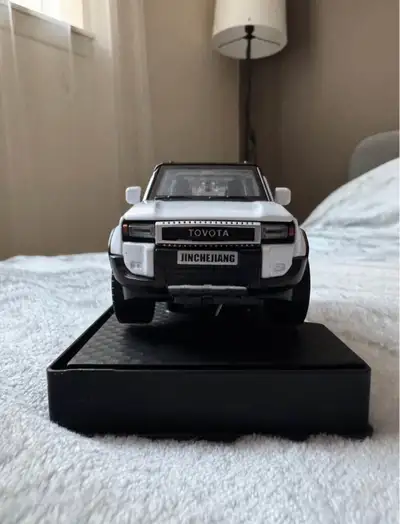 Brand new Toyota Land Cruiser model on a display stand. All doors, the trunk, and the hood open. The...