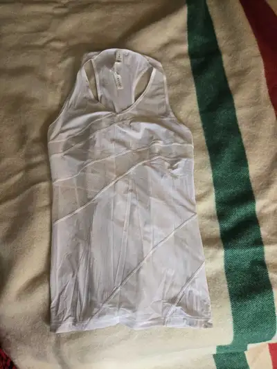 This is a used Lululemon white athletic tank top, size 8, perfect for workouts or casual wear, with...