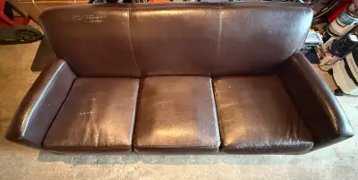 This brown, leather-like sofa is ready to find a new home! It's a sturdy piece with a classic design...