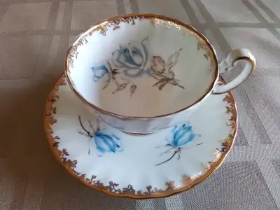 FINE BONE CHINA FOOTED CUP AND SAUCER - AYNSLEY, ENGLAND. WHITE AND GOLD WITH BLUE ROSE. IN VERY GOO...