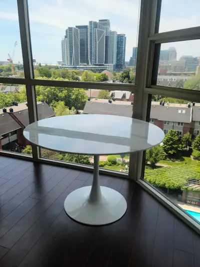This used dining table features a sleek, modern design with a white, round top and a matching white...
