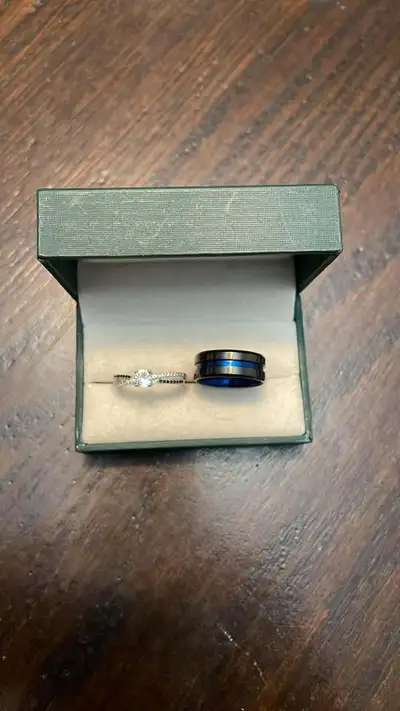 For sale is a wedding set featuring a women's ring and a men's ring with a blue accent. The women's...