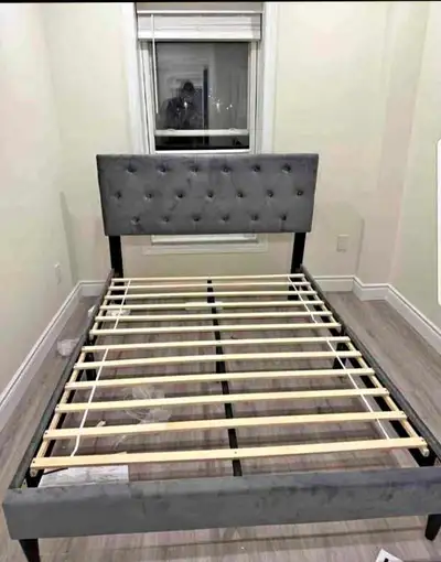 This is a used queen size bed frame, with a gray tufted headboard and wooden slats for support, prov...