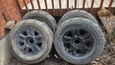 Set of 4 Goodyear Wrangler tires mounted on black 18" truck rims. Tire size: LT275/65R18 Load rating...