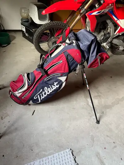 Titleist golf bag with bag cover. All straps are intact and all zippers work. General wear and tear...