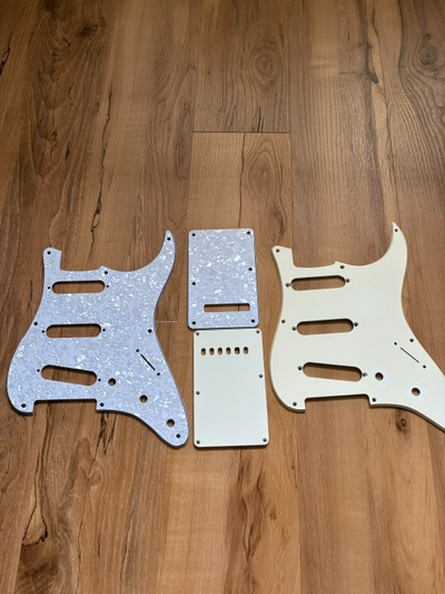 2 stratocaster pickguards with matching trem covers and screws. New white pearloid Off white vintage...