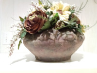 Fleurs artificielles montées dans un contenant en poterie.