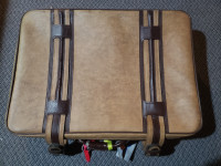 Large faux leather suitcase with buckle straps and wheels