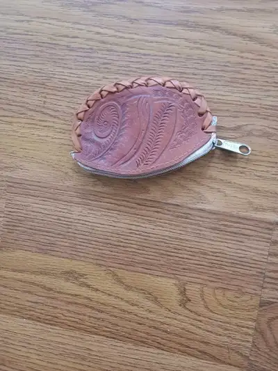 This is a used, tooled leather coin purse with a zipper closure. It's perfect for keeping your chang...